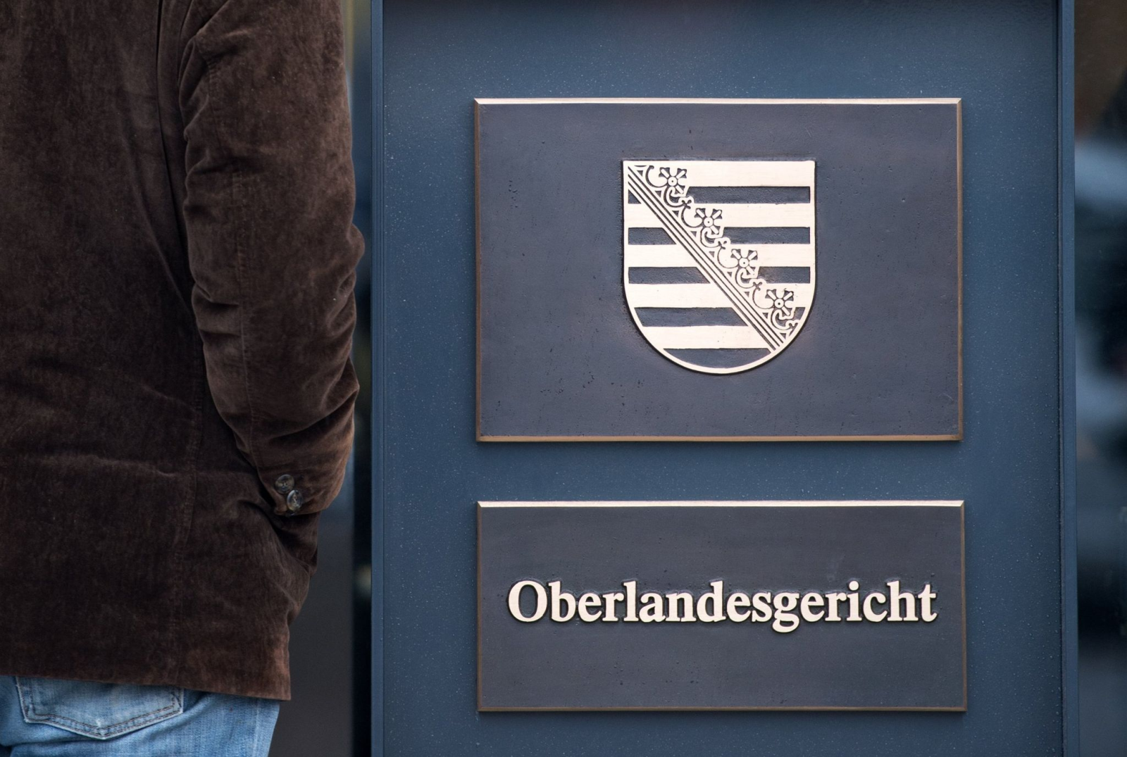 Ein Mann schaut in den Eingangsbereich des Gerichtsgebäudes des Oberlandesgerichts (OLG) in Dresden.