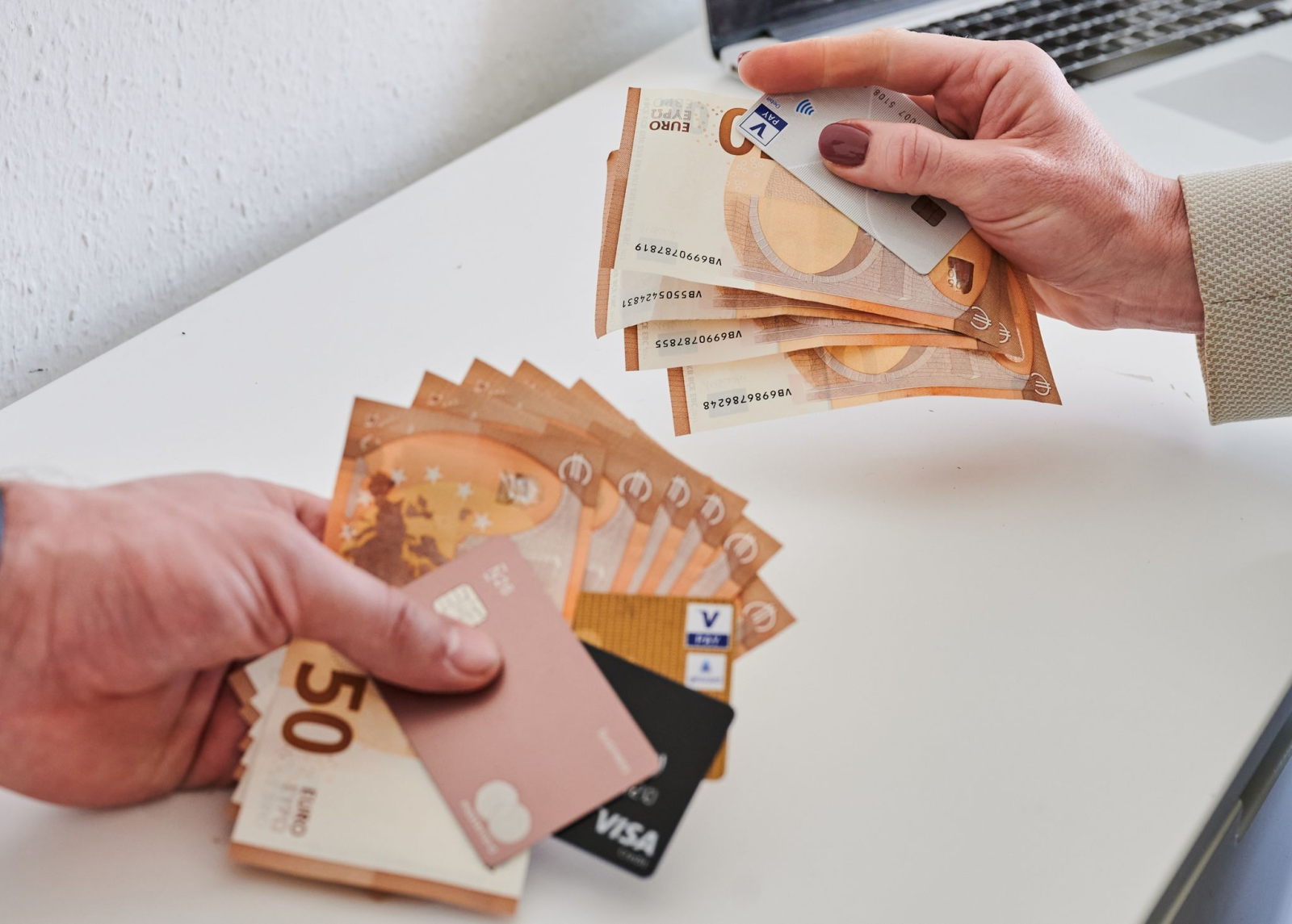 Ein Mann (l) und eine Frau halten eine unterschiedliche Anzahl von Geldscheinen und Karetn in den Händen.