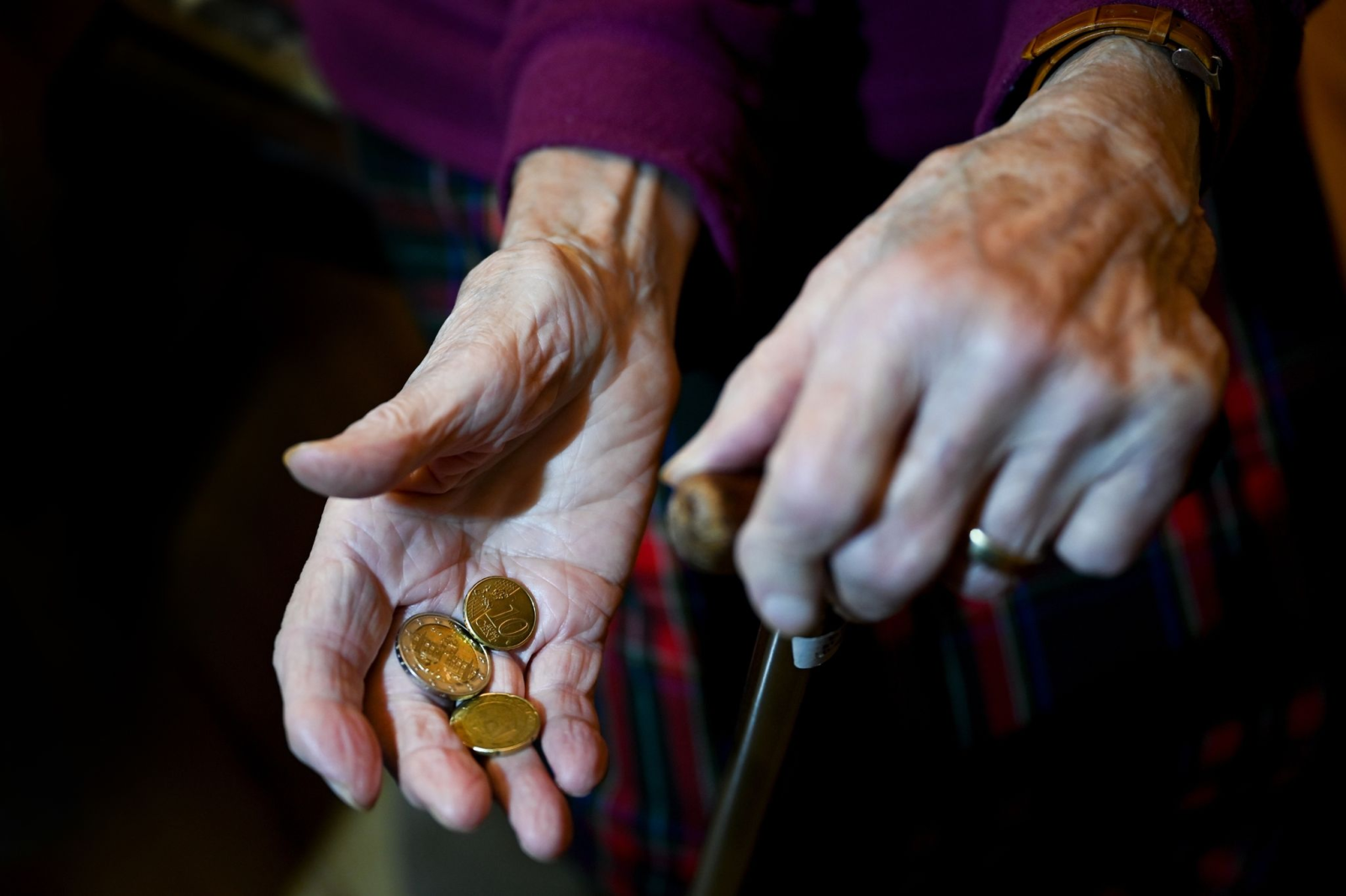 Eine alte Frau hält Kleingeld in der Hand.
