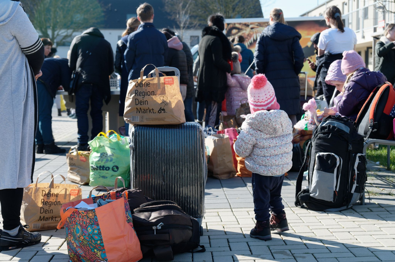 Geflüchtete aus der Ukraine stehen mit ihrem Gepäck vor den Gebäuden eines Flüchtlingsheims.