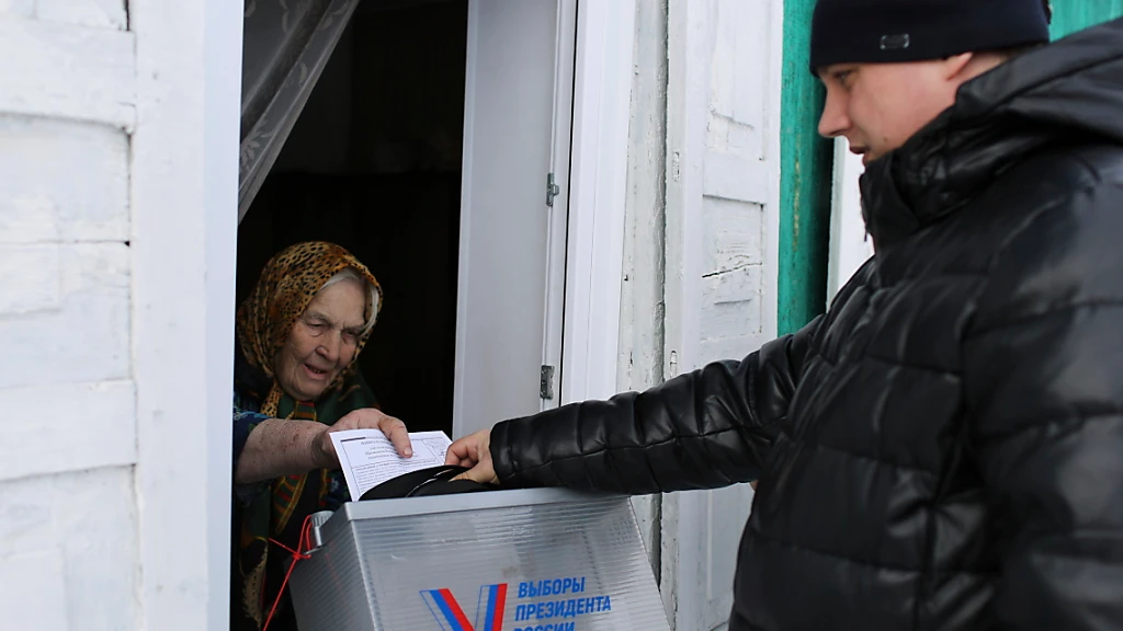 Eine ältere Frau gibt mit Hilfe eines mobilen Wahlkomitees ihre Stimme ab. Die Wähler in Russland gehen zu den Urnen, um an den Präsidentschaftswahlen teilzunehmen, bei denen es so gut wie sicher ist, dass die Präsidentschaft von Putin verlängert wird. , © ---/AP/dpa Eine ältere Frau gibt mit Hilfe eines mobilen Wahlkomitees ihre Stimme ab. Die Wähler in Russland gehen zu den Urnen, um an den Präsidentschaftswahlen teilzunehmen, bei denen es so gut wie sicher ist, dass die Präsidentschaft von Putin verlängert wird. , © ---/AP/dpa