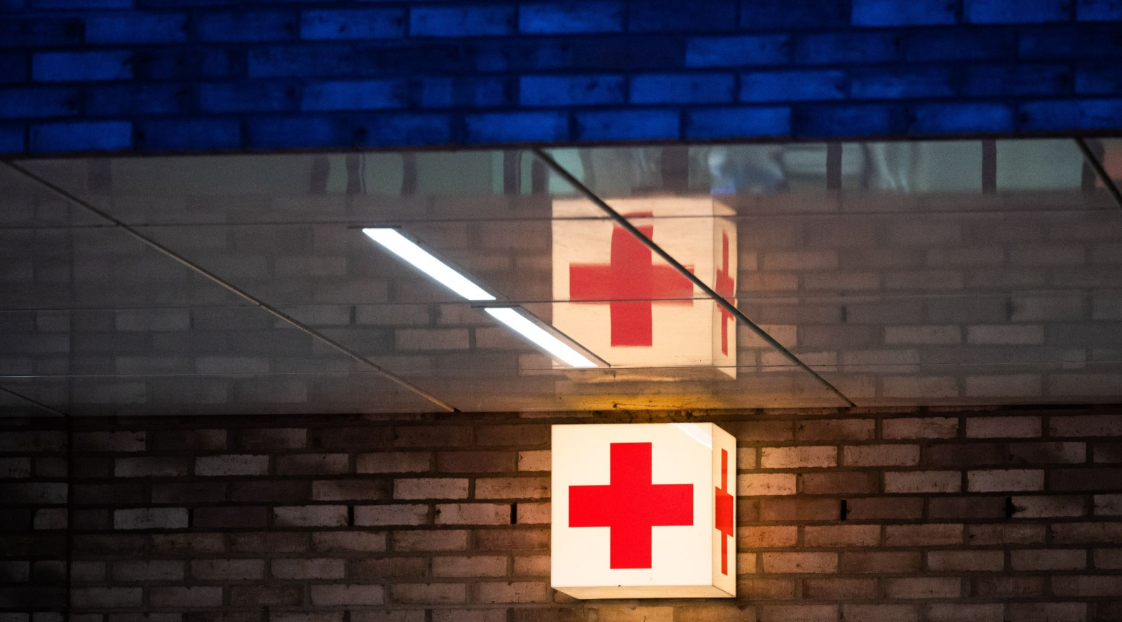 Ein Leuchtkasten mit einem roten Kreuz hängt vor der Notaufnahme eines Krankenhauses., © Julian Stratenschulte/dpa/Symbolbild