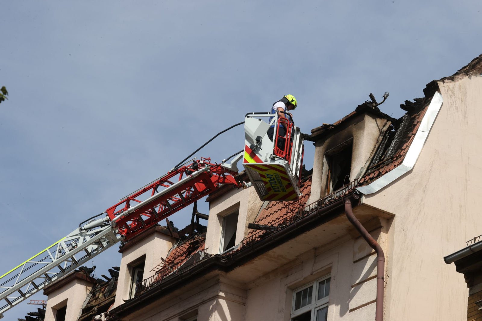 Feuerwehrleute und Statiker untersuchen das Dach des Mehrfamilienhauses.