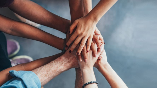 Hände aufeinandergelegt und grauen Fußboden zu sehen, © Shutterstock