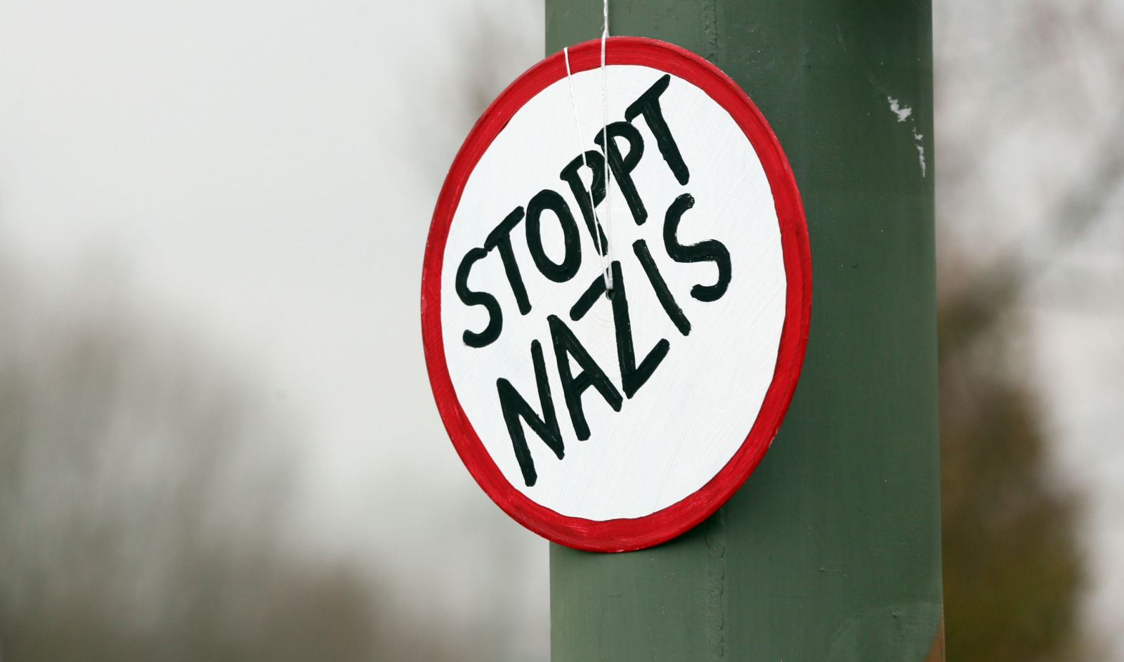 Ein Schild mit der Aufschrift «Stoppt Nazis» hängt am Rande einer Demo an einem Laternenmast.