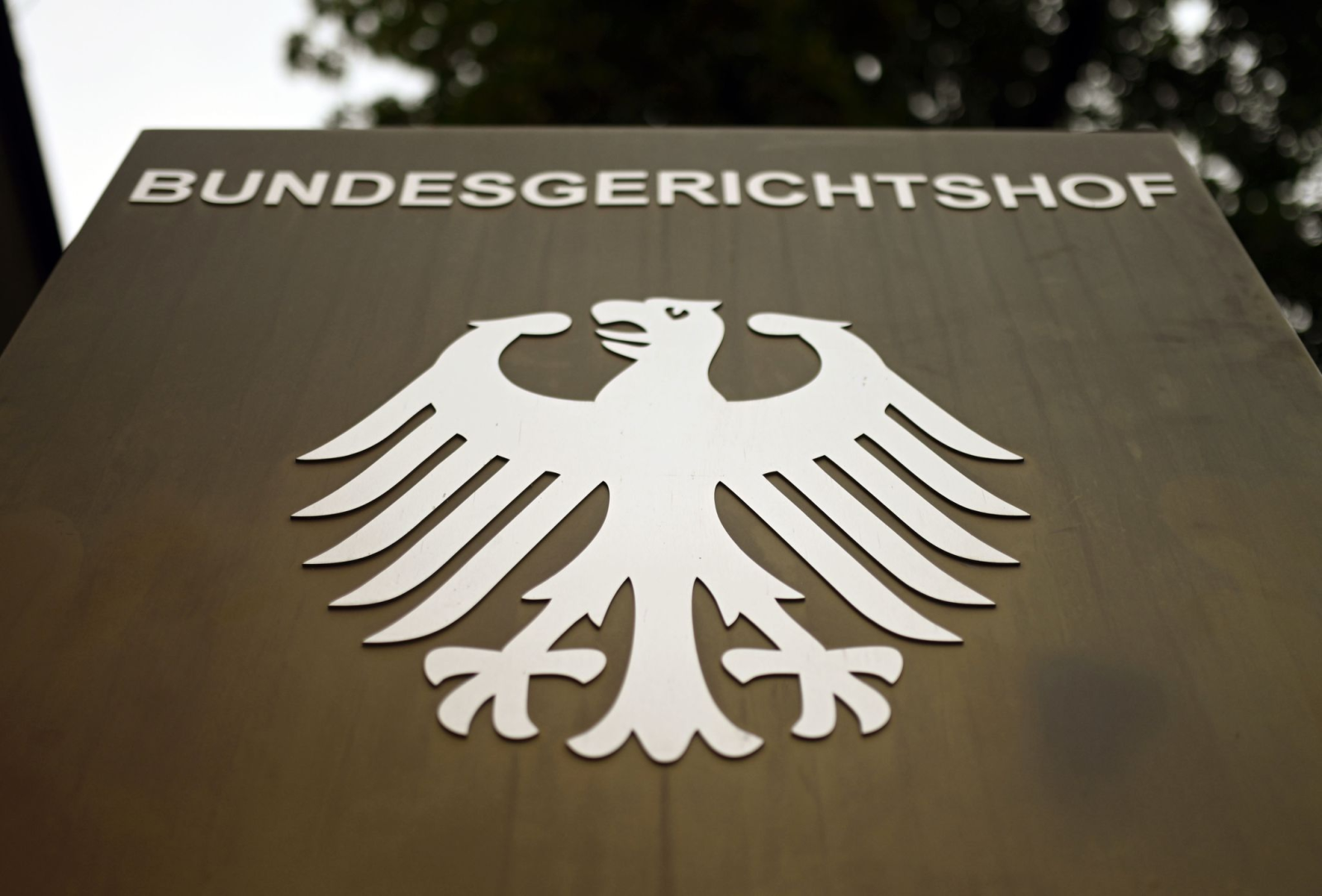 Ein Hinweisschild mit dem Bundesadler steht vor dem Bundesgerichtshof (BGH) in Karlsruhe.