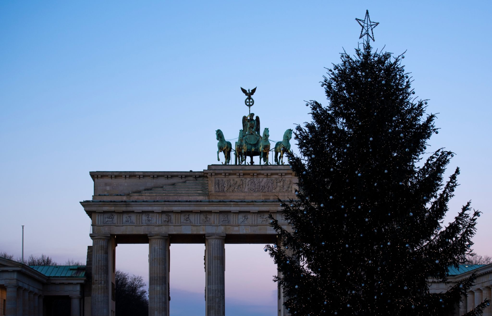 Hinter einem geschmückten Weihnachtsbaum steht das Brandenburger Tor am Weihnachtstag.