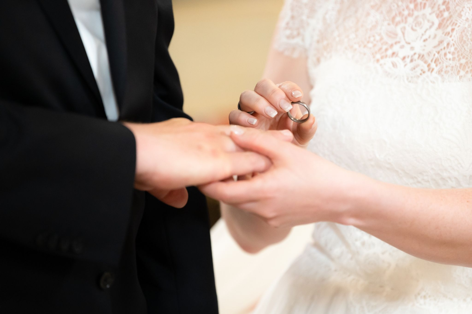 Ein Brautpaar steckt sich während ihrer Trauung in der Kirche die Ringe an.