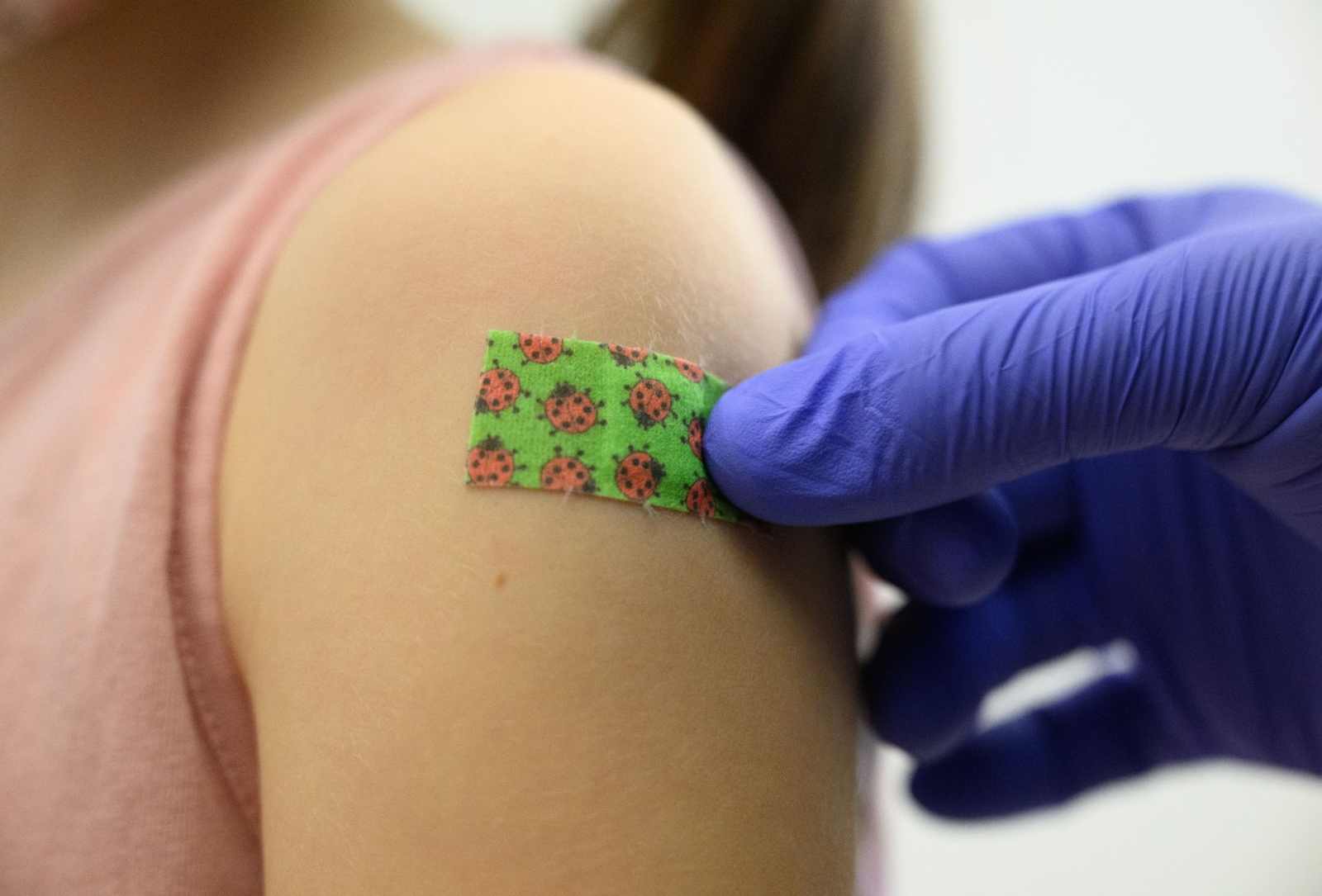 Ein siebenjähriges Mädchen bekommt nach der Impfung gegen Covid ein Pflaster auf den Arm geklebt.