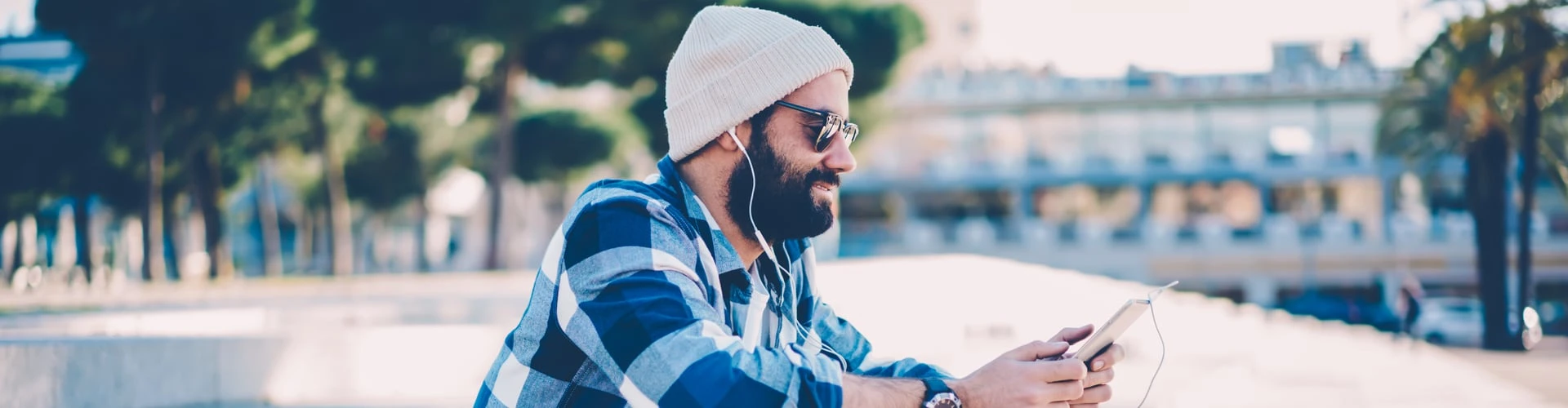 Mann im karierten Hemd hört Musik und hat eine Mütze dabei auf, © Shutterstock Mann im karierten Hemd hört Musik und hat eine Mütze dabei auf, © Shutterstock