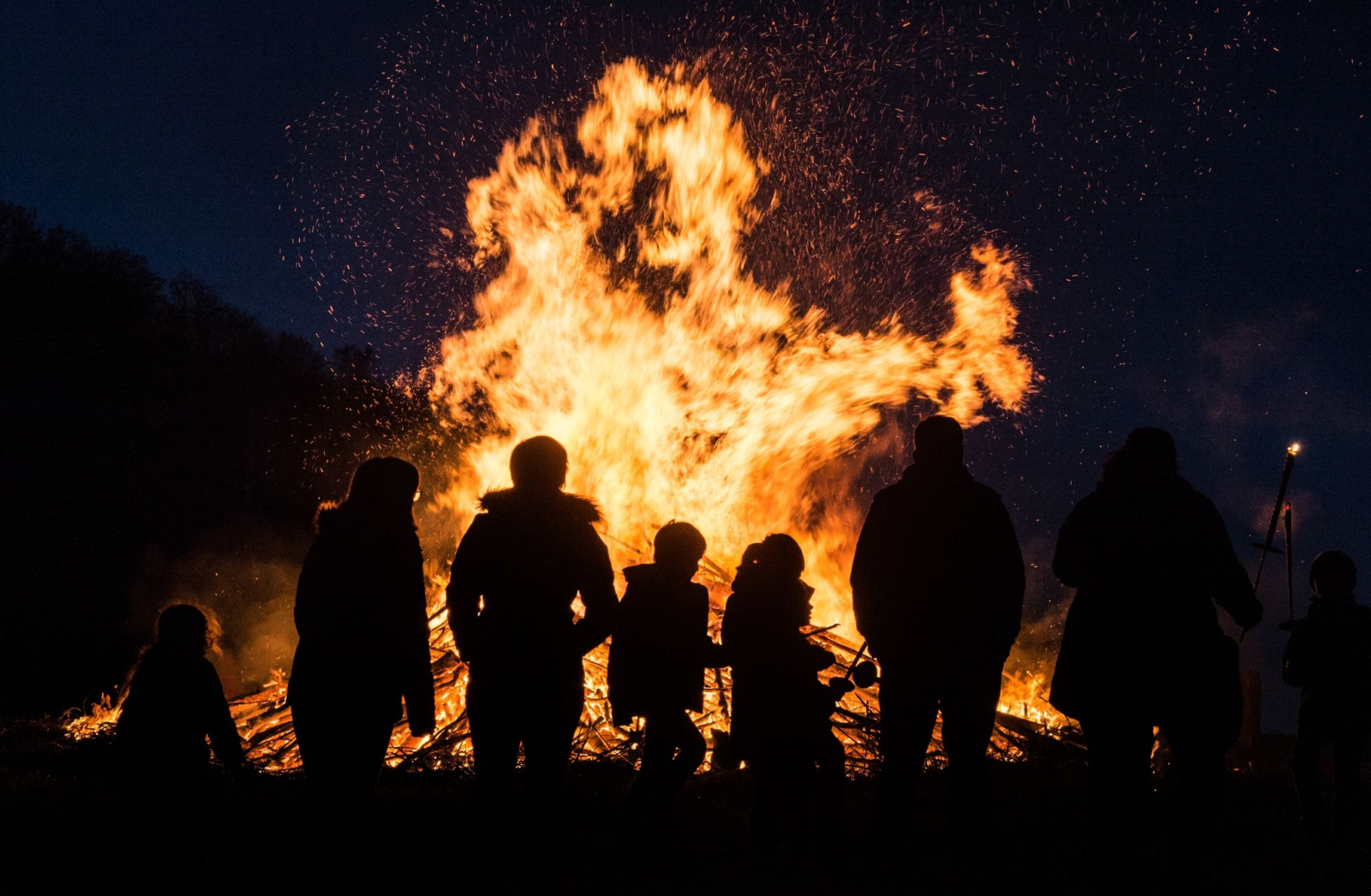 Menschen stehen an einem traditionellen Osterfeuer.