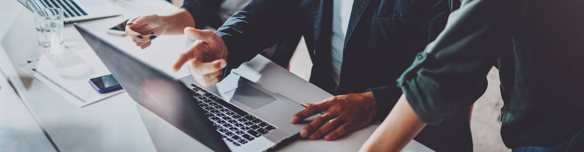 Menschen stehen vorm Laptop und zeigen mit dem Finger dadrauf, © Shutterstock