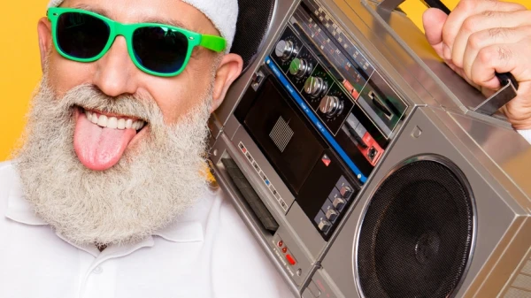 Mann mit weißen Bart streckt die Zunge heraus und hat eine Musikbox in der Hand, © Shutterstock Mann mit weißen Bart streckt die Zunge heraus und hat eine Musikbox in der Hand, © Shutterstock