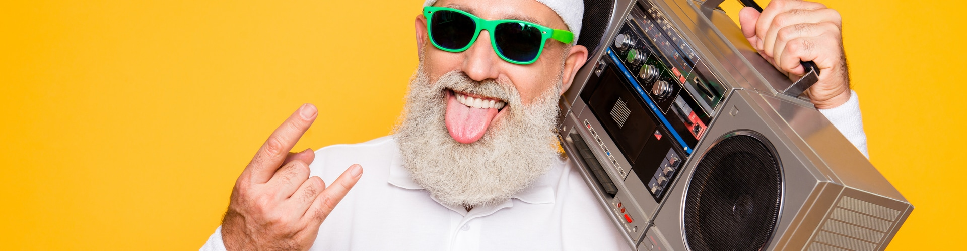 Mann mit weißen Bart streckt die Zunge heraus und hat eine Musikbox in der Hand, © Shutterstock