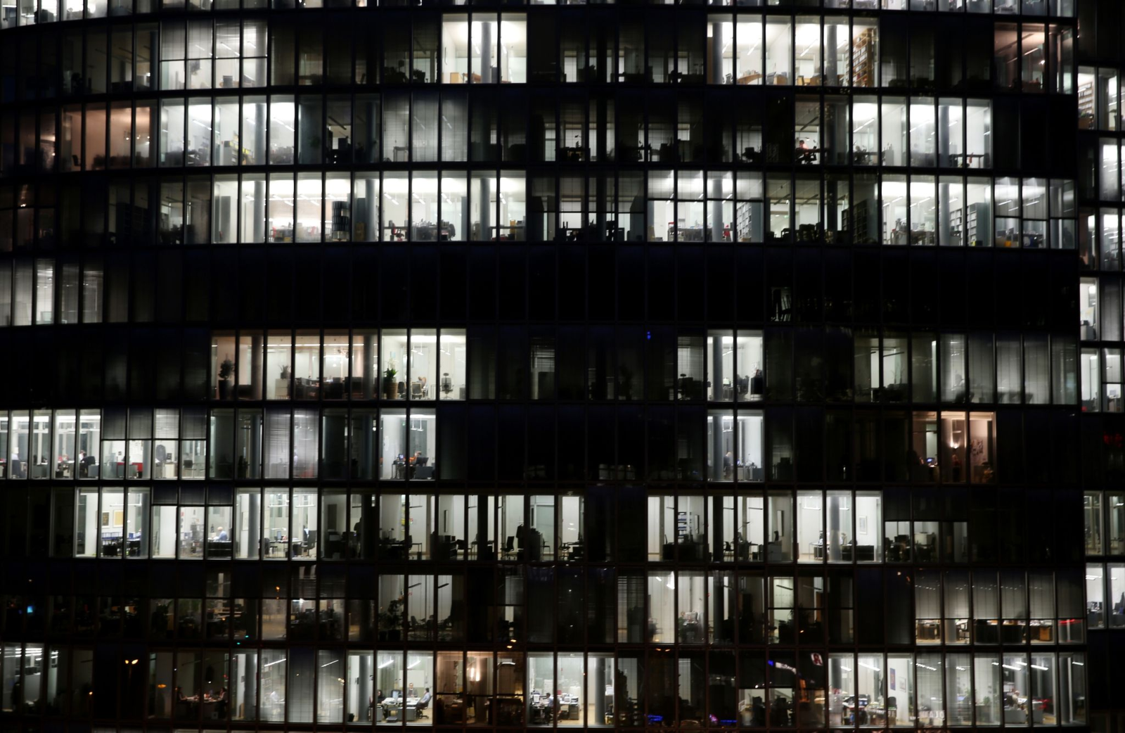 In einem Bürohochhaus sind am Abend zahlreiche Büros beleuchtet, in denen noch gearbeitet wird.