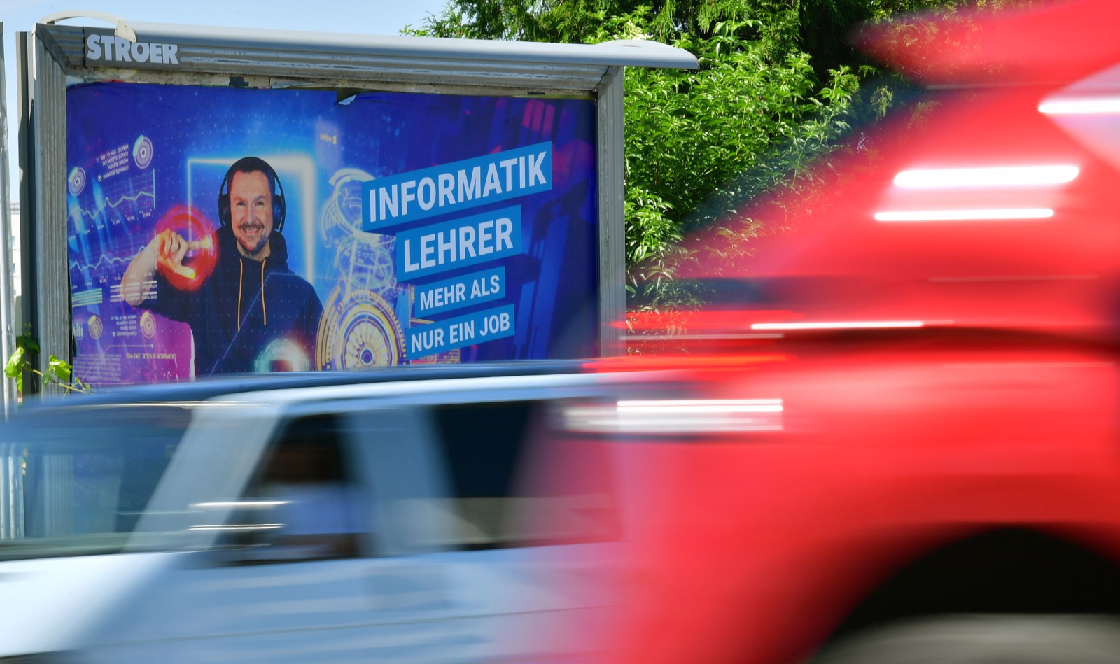 Autos fahren an einem Plakatmotiv der Thüringer Lehrergewinnungskampagne vorbei.